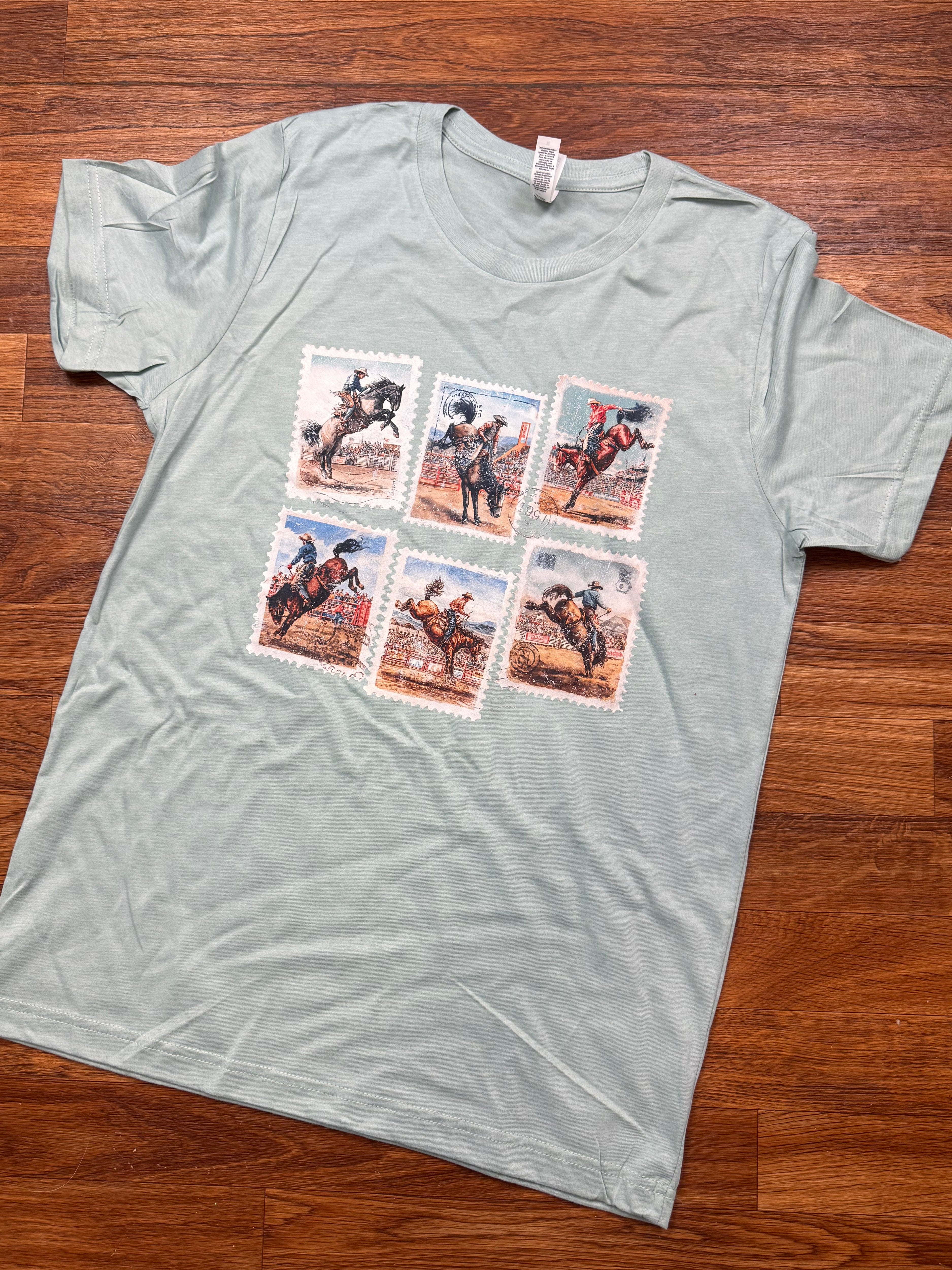 Sea foam green t-shirt with graphic designs on a wooden floor