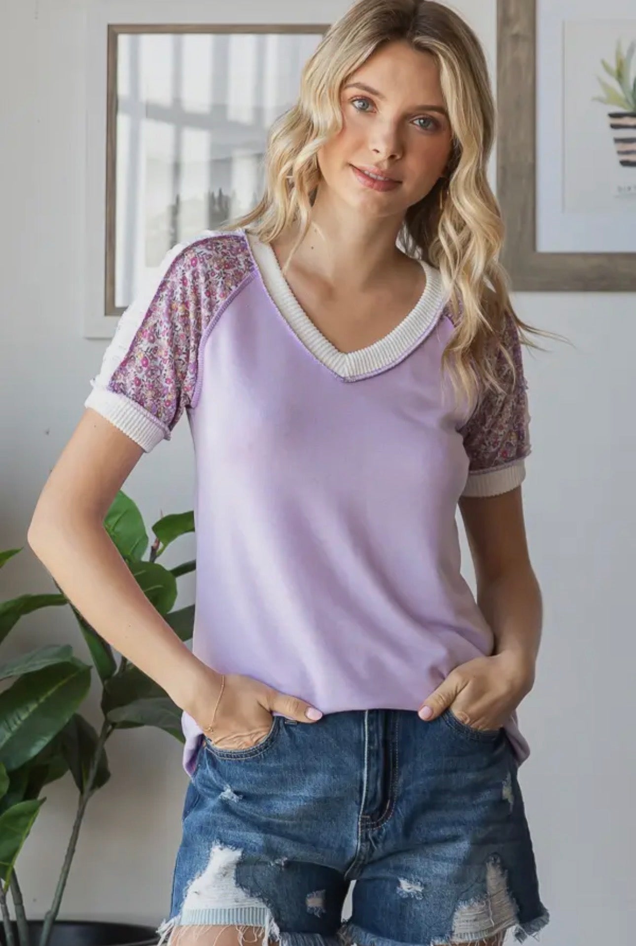 Woman wearing a purple lace-trimmed top and denim shorts indoors.