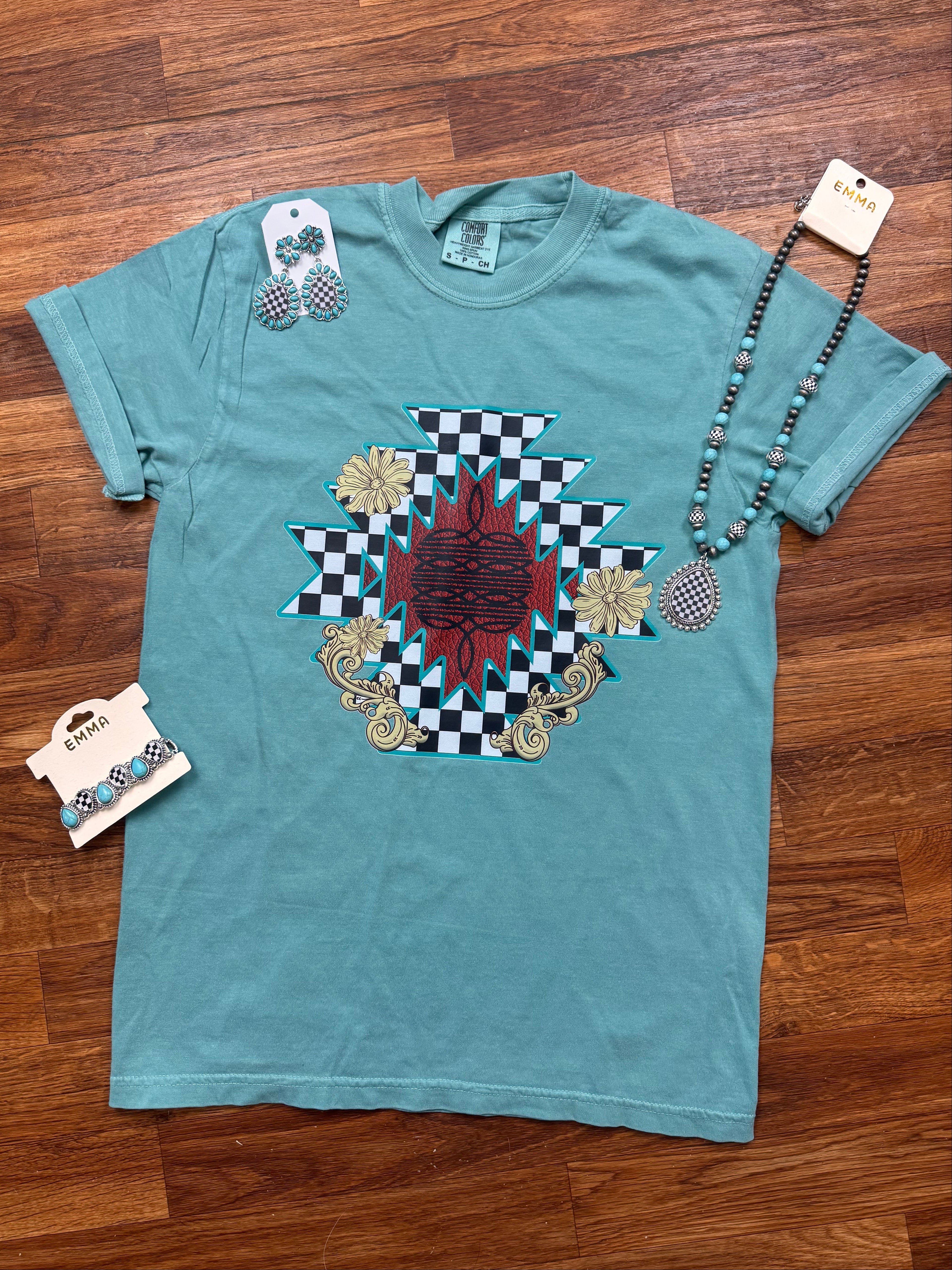 Teal t-shirt with a decorative design on a wooden floor